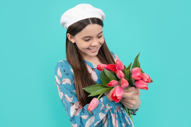 Bambino felice in berretto con tulipani madri o festa della donna bambino tenere fiori per l'8 marzo