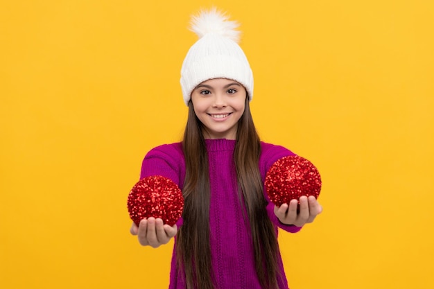 Bambino felice in cappello invernale con palla decorativa, natale.