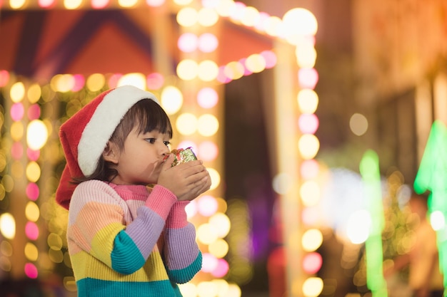 Bambino felice in cappello rosso della Santa che tiene i regali di Natale. Periodo natalizio.