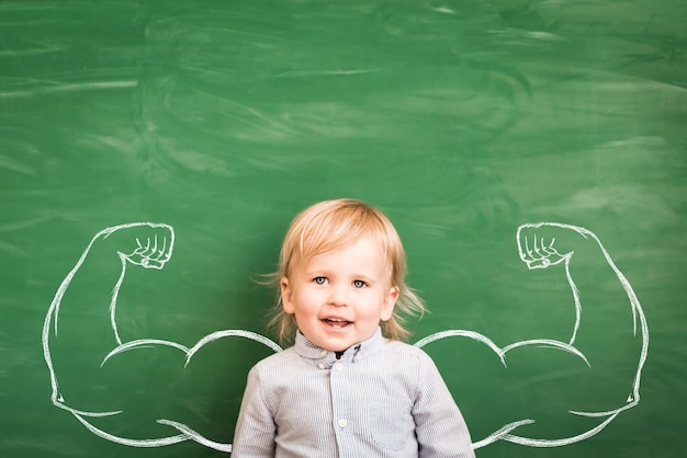 Bambino felice in classe. Bambino divertente contro la lavagna. Di nuovo a scuola. Concetto di educazione