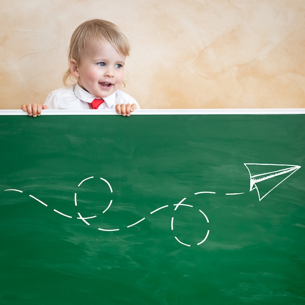 Bambino felice in classe. Bambino divertente contro la lavagna. Di nuovo a scuola. Concetto di educazione