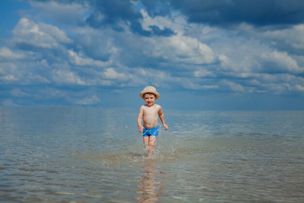 Bambino felice in esecuzione da surf sulla spiaggia