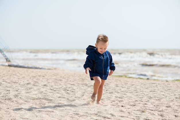 Bambino felice in esecuzione in giacca sulla sabbia