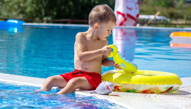 Bambino felice in piscina che gioca con una pistola ad acqua.