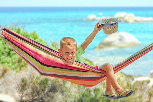 Bambino felice in riva al mare sull'amaca