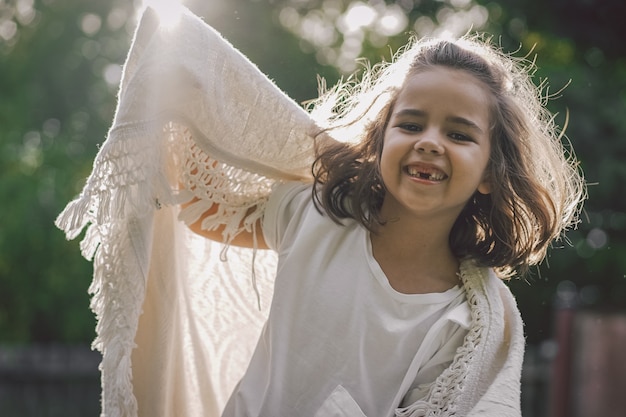 Bambino felice. Ragazza divertente che gioca con una coperta. Ragazza sorridente del bambino. Allegro bambino all'aperto nella natura