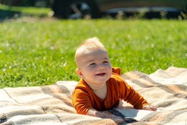 Bambino felice sdraiato sulla coperta sull'erba soleggiata Bambino all'aperto