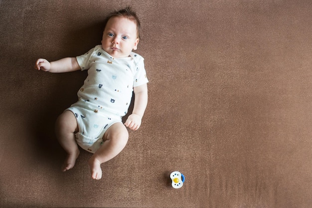 Bambino felice sveglio di 7 mesi in pannolino che si trova e che gioca