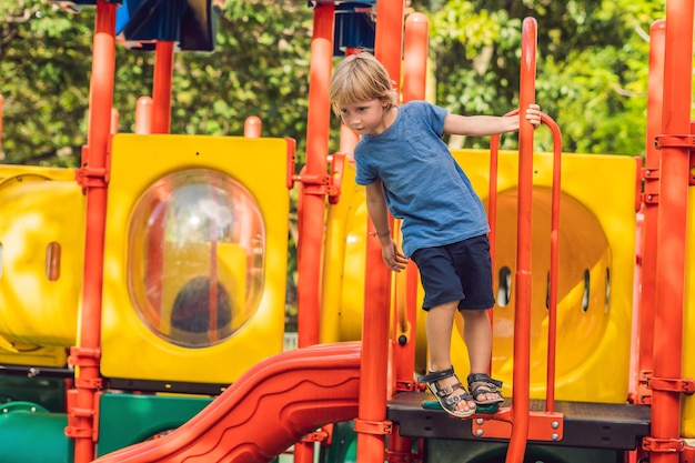 Bambino felice sveglio divertente che gioca nel parco giochi. L'emozione della felicità, del divertimento, della gioia