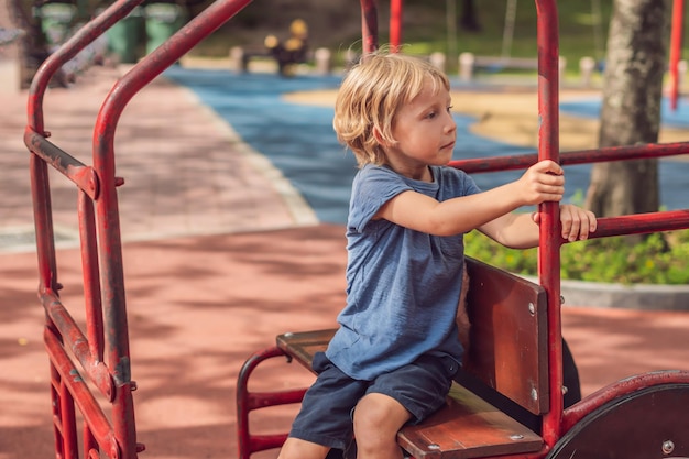 Bambino felice sveglio divertente che gioca nel parco giochi. L'emozione della felicità, del divertimento, della gioia