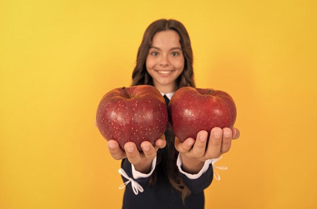 Bambino felice tenere mela vitamina rossa per pranzo su sfondo giallo messa a fuoco selettiva dieta