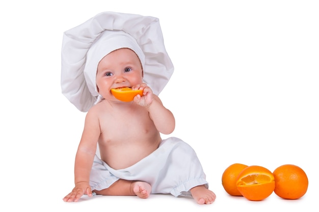 bambino in abiti da chef sta mangiando arancia