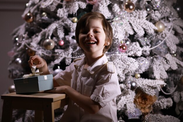 Bambino in abiti eleganti davanti all'albero di Natale. Aspettando il nuovo anno.