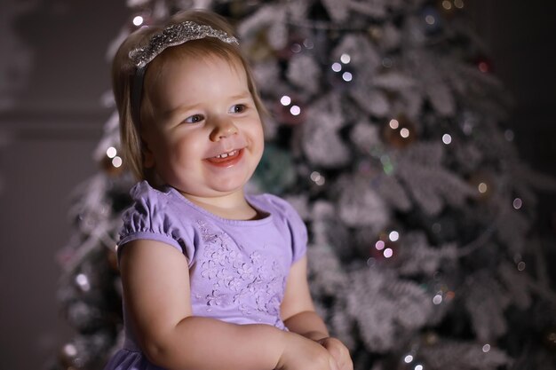 Bambino in abiti eleganti davanti all'albero di Natale In attesa del nuovo anno