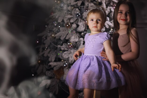 Bambino in abiti eleganti davanti all'albero di Natale. Vigilia di Capodanno. Aspettando il nuovo anno.