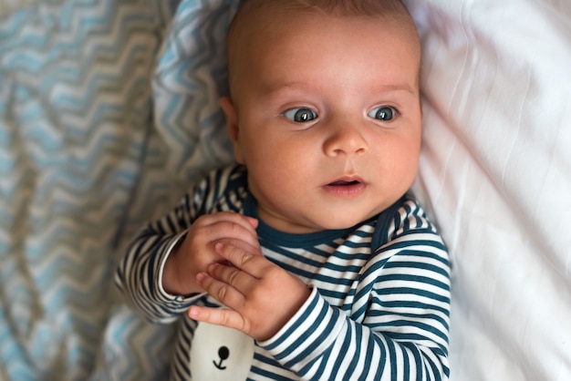 Bambino in abiti sdraiato sul letto Ritratto di Close-up di un bambino carino