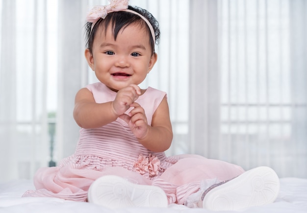 Bambino in abito rosa sul letto