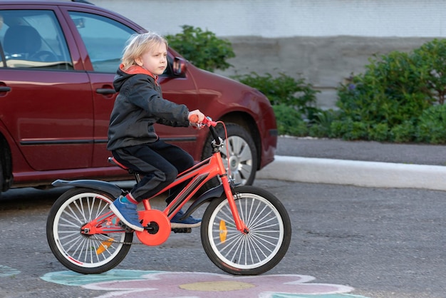 Bambino in bicicletta su strada asfaltata vicino all'auto Sicurezza dei bambini