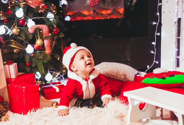 Bambino in costume da Babbo Natale gioca alle decorazioni di Natale