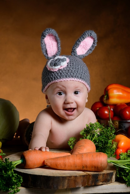 Bambino in costume da coniglio con verdure su un legno