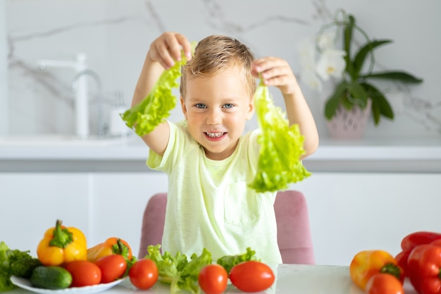 bambino in cucina a casa a mangiare verdure bambino sorridente concetto di mangiare sano vegetariano