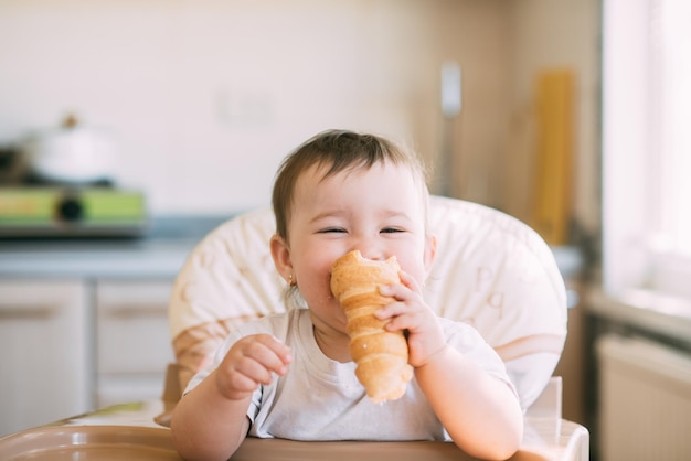 Bambino in cucina che mangia avidamente le deliziose corna alla crema, ripiene di una crema alla vaniglia