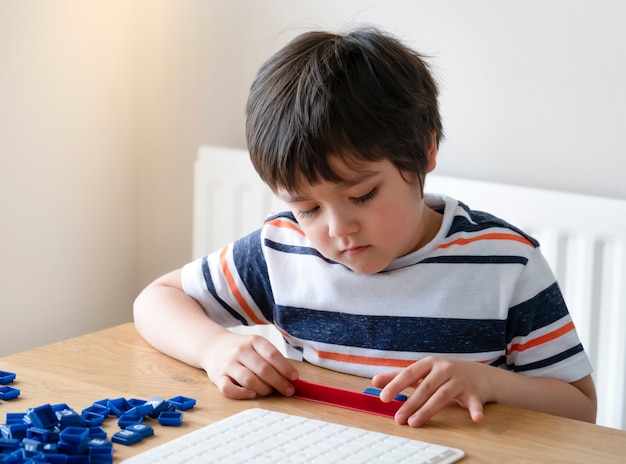 Bambino in età prescolare che gioca il gioco di parole inglesi, ragazzo del bambino concentrato con l'ortografia della lettera inglese con il genitore a casa. Attività per bambini per giocare e imparare, concetto di educazione e homeschooling