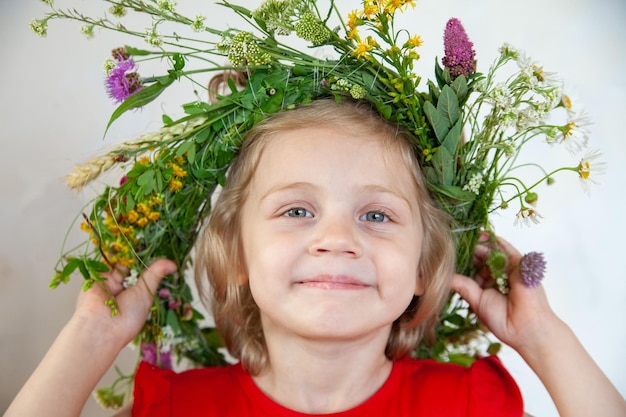 Bambino in ghirlanda di fiori selvatici