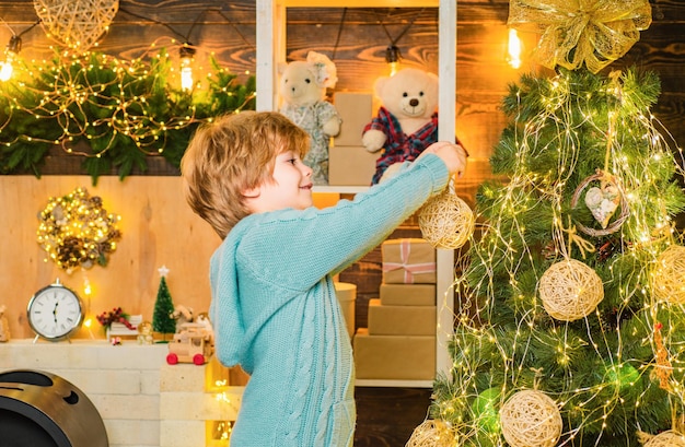 Bambino in inverno vestito di Natale decorare l'albero di Natale con gioielli Bambino decorare l'albero di Natale e divertirsi