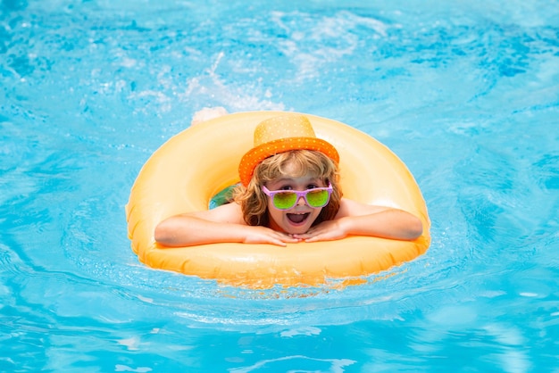 Bambino in occhiali da sole in piscina in un giorno d'estate Bambini che giocano in piscina Vacanze estive e concetto di vacanza