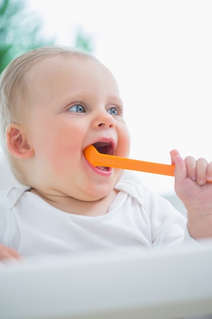 Bambino in possesso di un cucchiaio di plastica in bocca