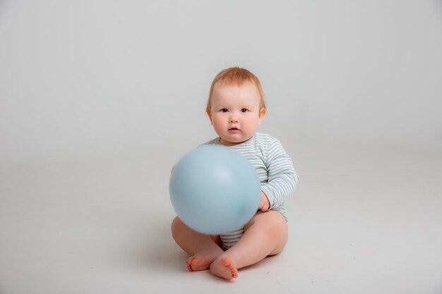 Bambino in possesso di un palloncino blu su sfondo bianco