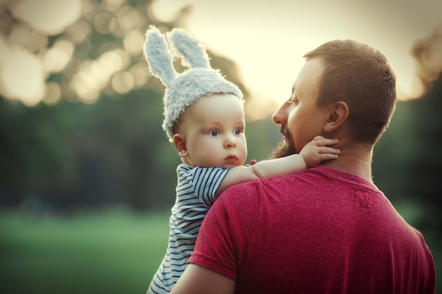 bambino in un buffo cappello con orecchie di coniglio tra le braccia di suo padre