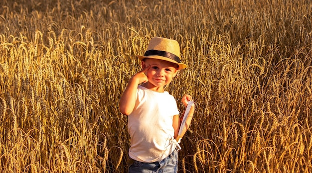 Bambino in un campo di grano che abbraccia un raccolto di grano. Natura, messa a fuoco selettiva