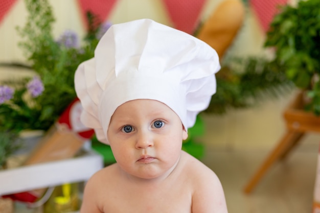 Bambino in un cappello da cuoco con cibo intorno a lui