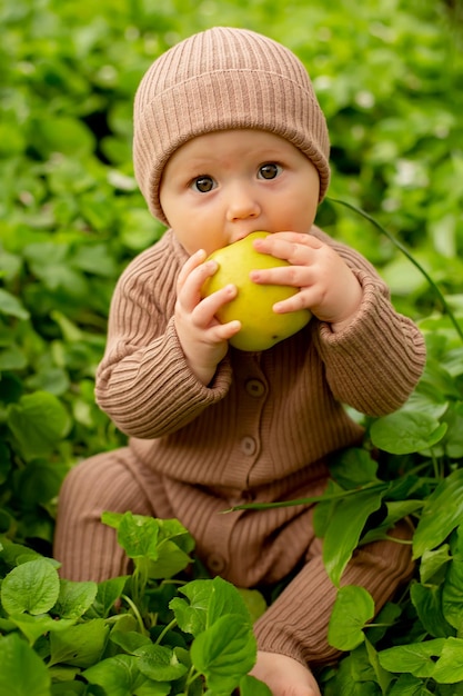 Bambino in un cappello marrone che mangia una mela