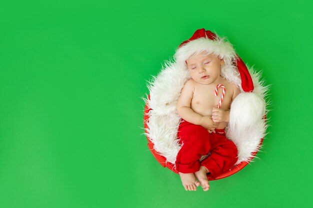 Bambino in un costume da Babbo Natale sdraiato su uno sfondo verde