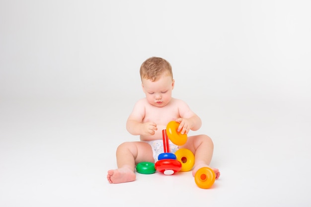 Bambino in un pannolino che gioca a piramide su uno sfondo bianco studio