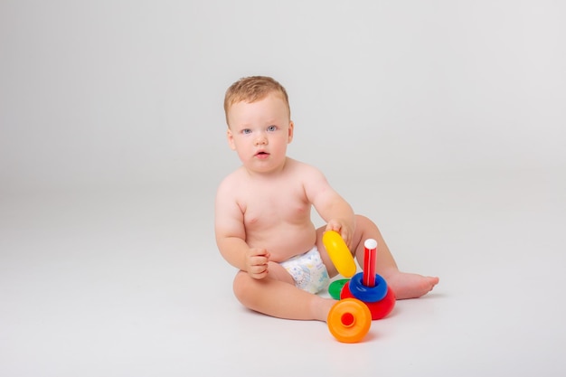 Bambino in un pannolino che gioca a piramide su uno sfondo bianco studio