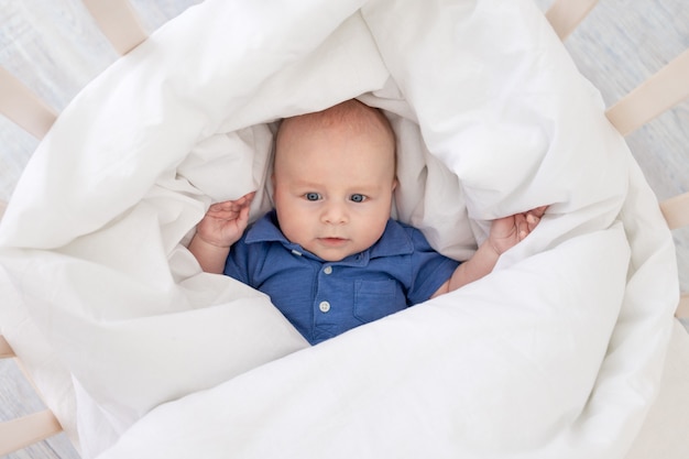 bambino in una coperta in una culla, neonato felice si sveglia al mattino o va a letto