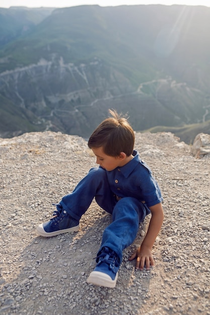 Bambino in una tuta di lino blu giace sulla scogliera del canyon di Sulak in Daghestan e pensa alla vita