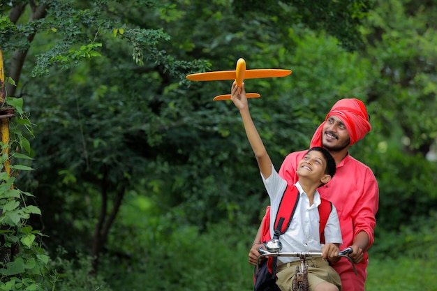 bambino indiano che gioca con l'aeroplano giocattolo con suo padre sul ciclo