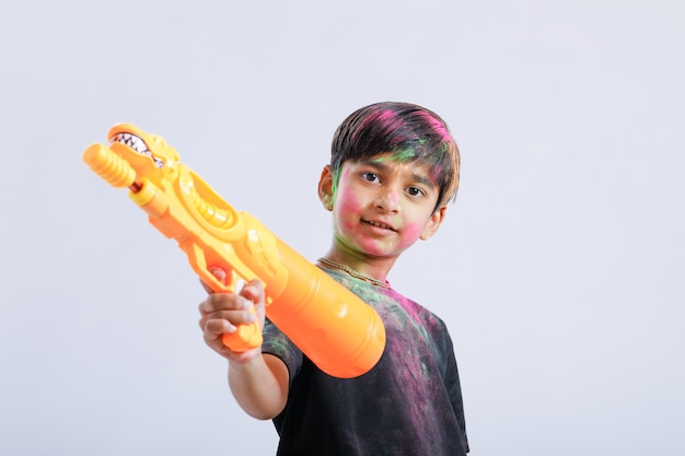 Bambino indiano che gioca holi con la pistola di colore