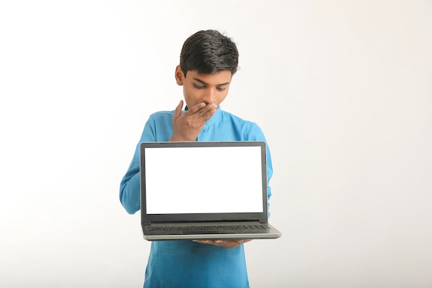 Bambino indiano che indossa un panno tradizionale e mostra lo schermo del laptop