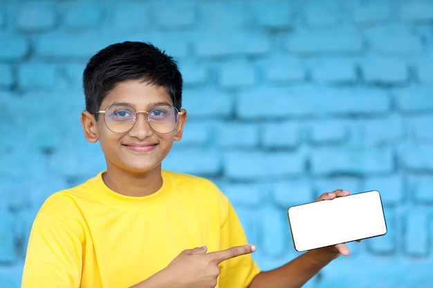 Bambino indiano che mostra lo schermo dello smartphone. concetto di educazione online
