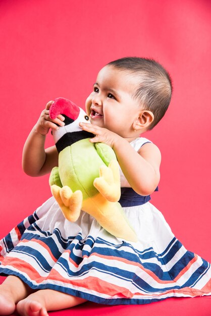 Bambino indiano o asiatico o neonato o bambino che gioca con giocattoli o blocchi mentre è sdraiato o seduto isolato su uno sfondo luminoso o colorato