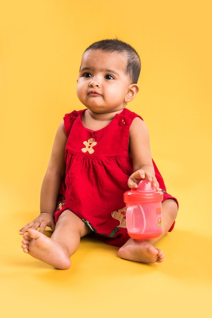 Bambino indiano o asiatico o neonato o bambino che gioca con giocattoli o blocchi mentre è sdraiato o seduto isolato su uno sfondo luminoso o colorato