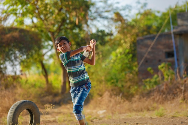 Bambino indiano rurale che gioca cricket