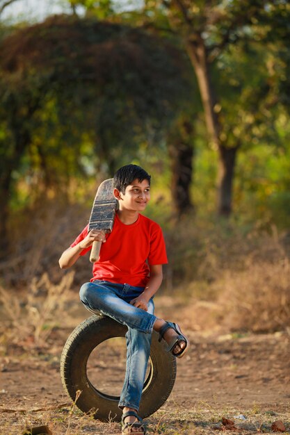 Bambino indiano rurale che gioca cricket