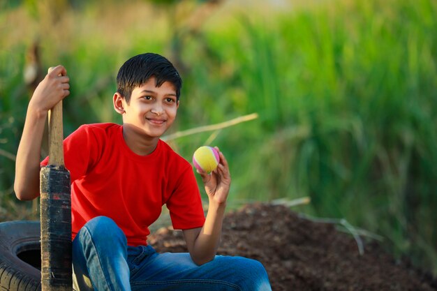 Bambino indiano rurale che gioca cricket
